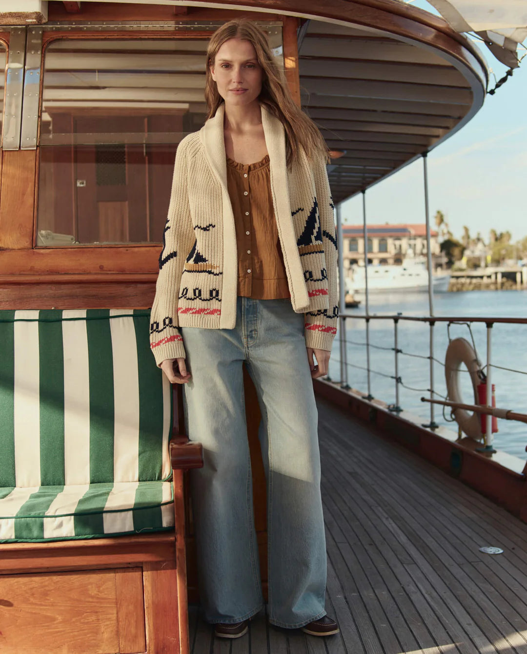 Woman on a boat wearing a patterned cardigan with a scenic background