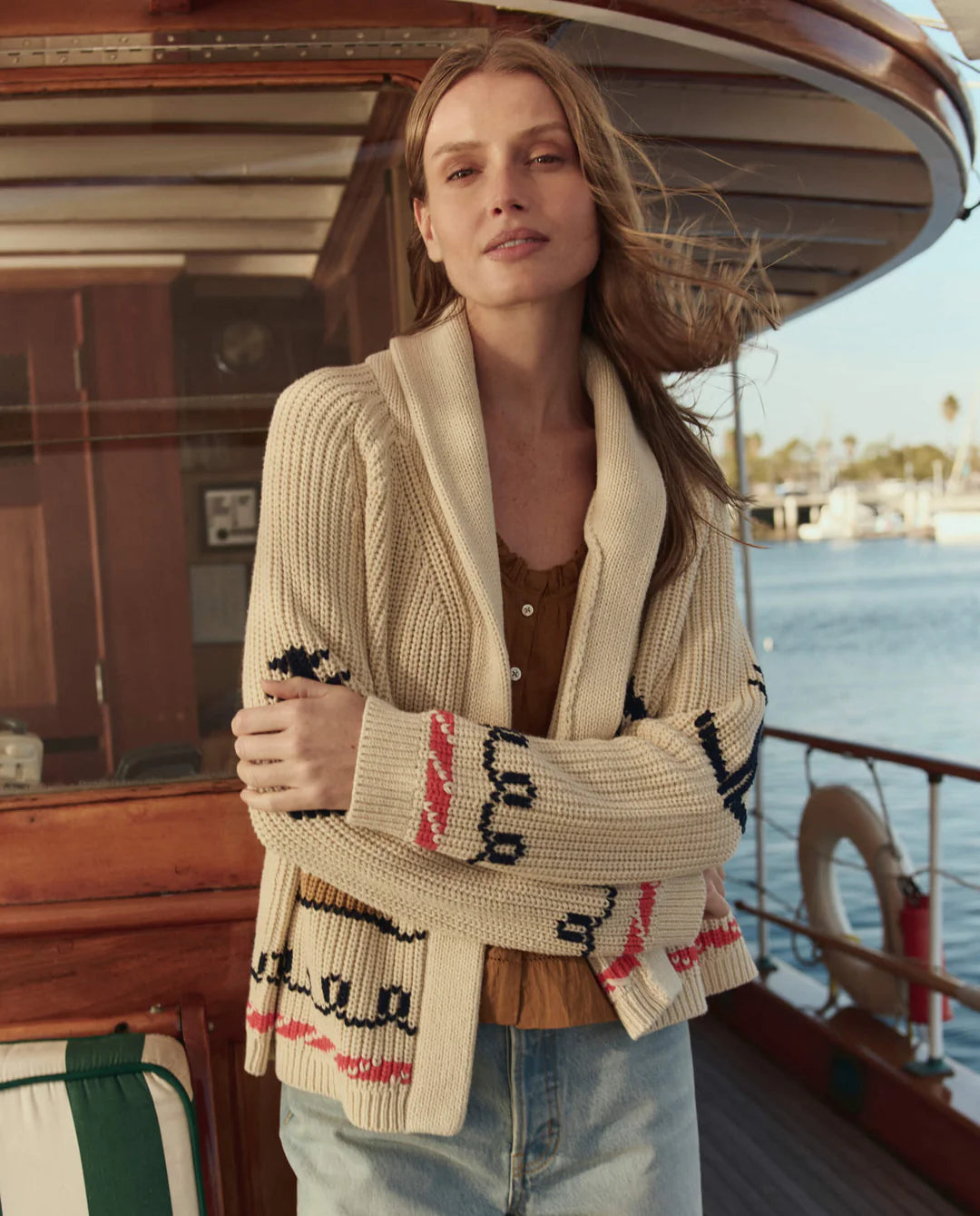 Woman wearing a patterned cardigan on a boat with water and sky in the background