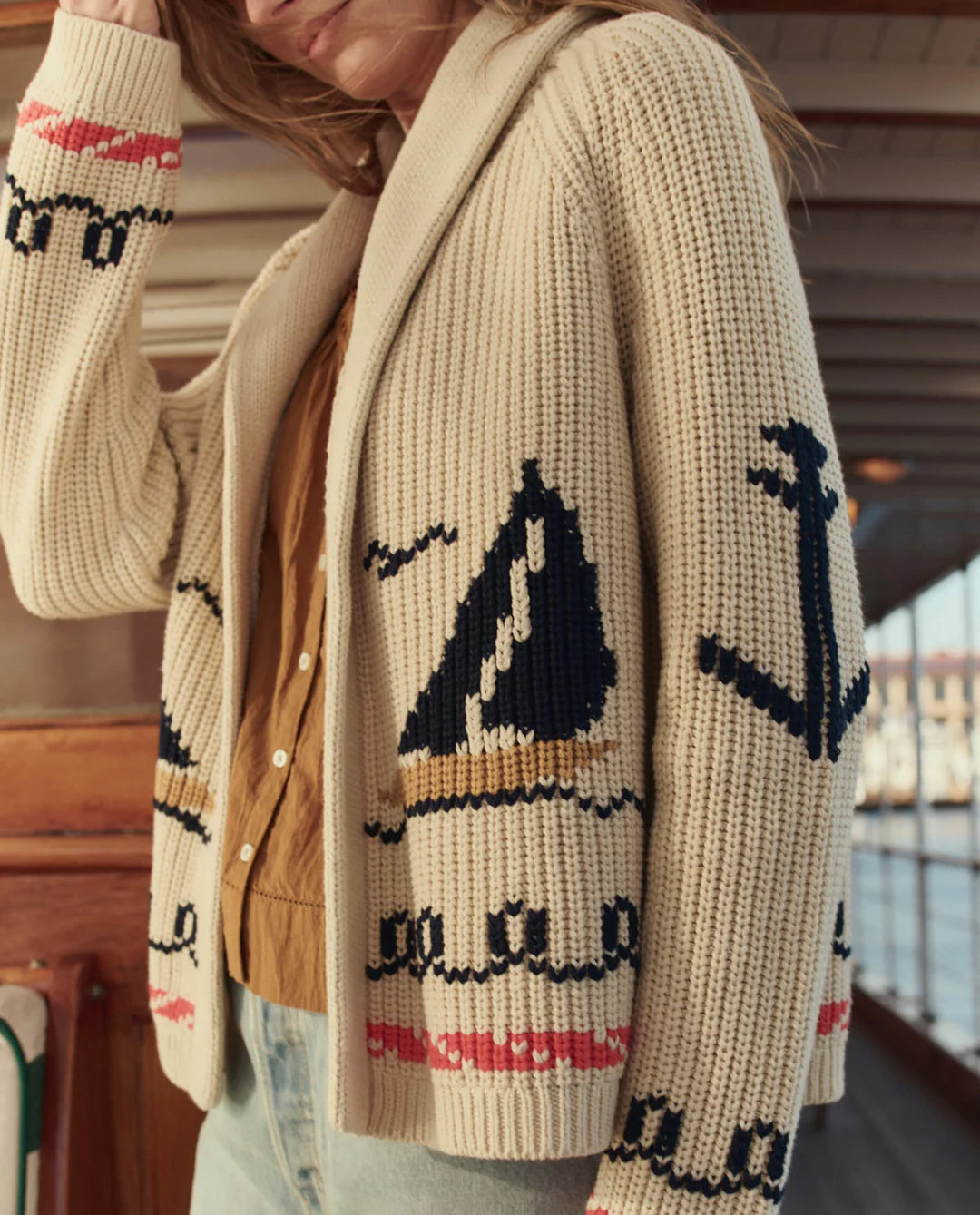 Person wearing a beige cardigan with whale pattern indoors