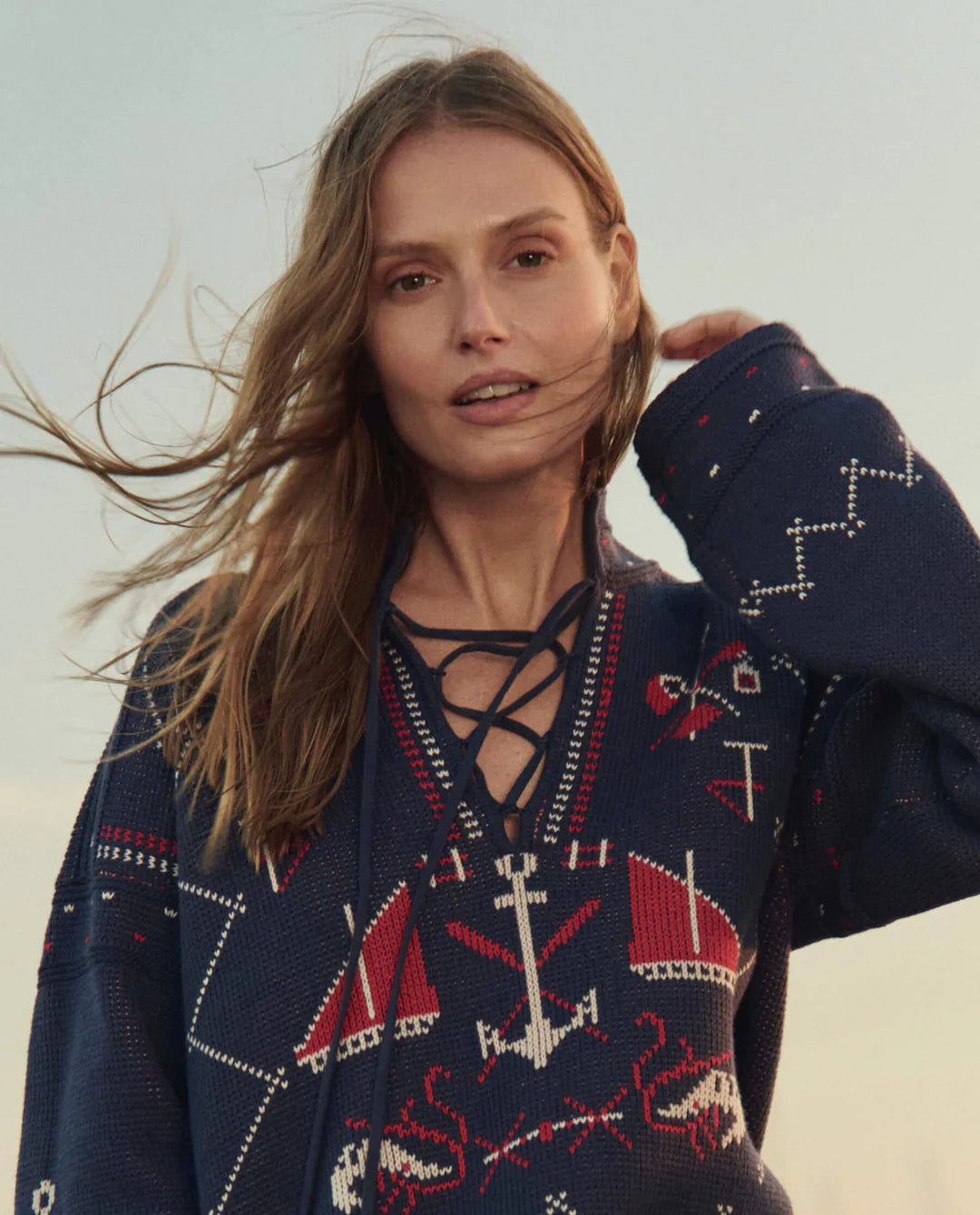 Woman wearing a navy sweater with red and white patterns against a light background