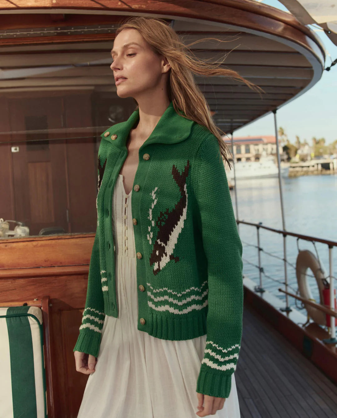 Woman wearing a green sweater with a bird design on a boat