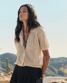Woman wearing a beige knitted cardigan with a desert landscape in the background