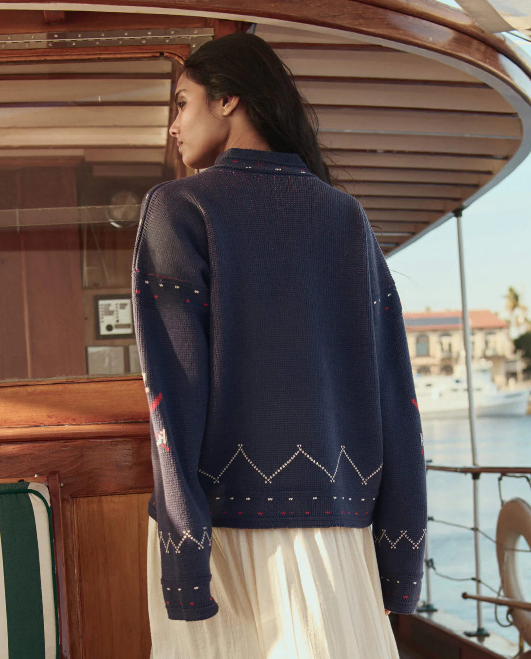 Woman wearing a navy blue sweater with white patterns on a boat deck.