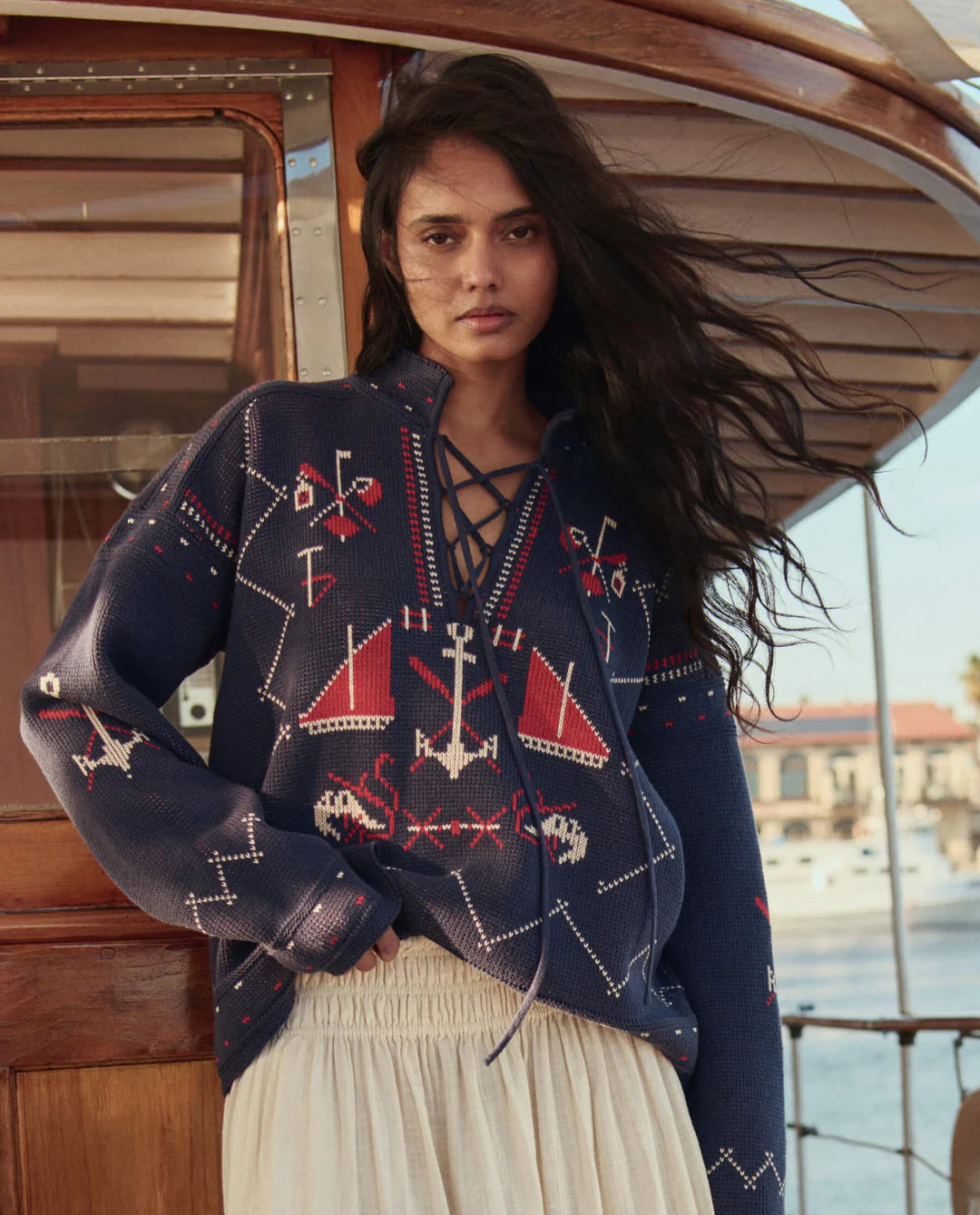 Woman wearing a navy blue sweater with red and white patterns on a boat.