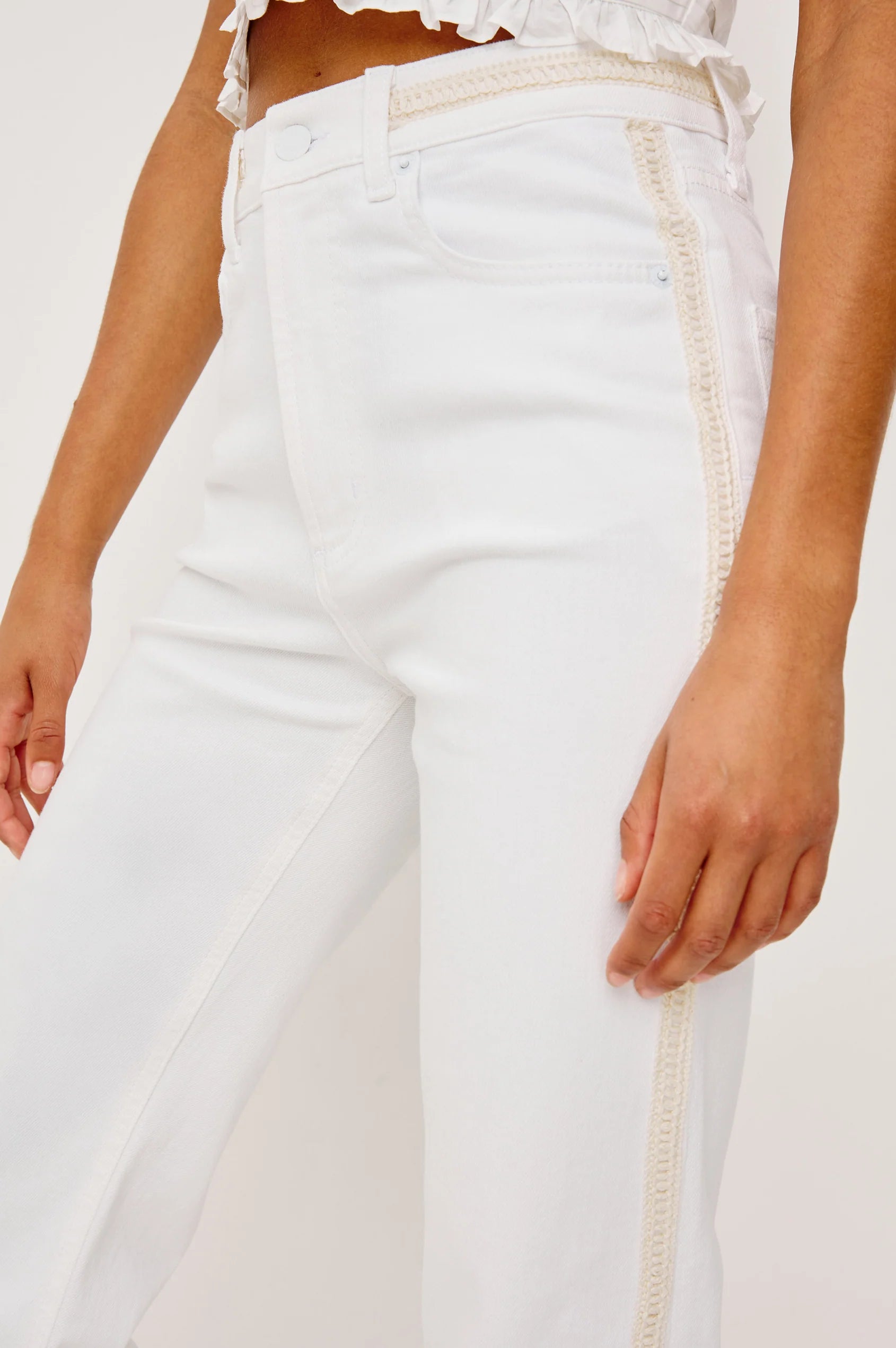 White pants with decorative trim on a white background