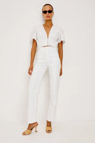 Woman wearing a white outfit with sunglasses on a plain background