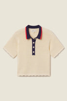 Beige textured polo shirt with navy collar and buttons on a beige background