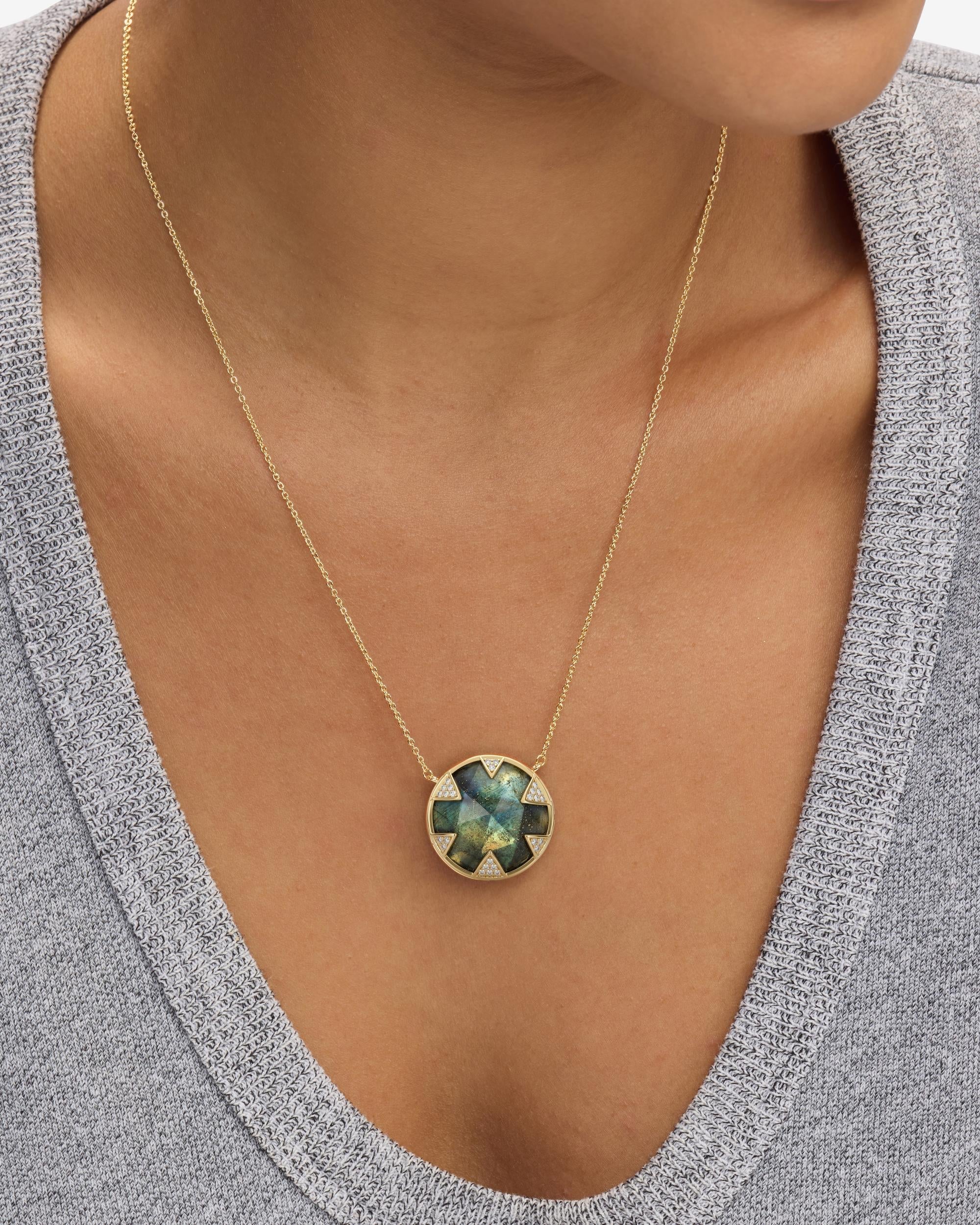 Necklace with a green gemstone pendant worn by a person in a gray top.