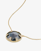 Gold necklace with a dark gemstone pendant on a white background