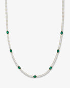 Gold necklace with green gemstones on a white background