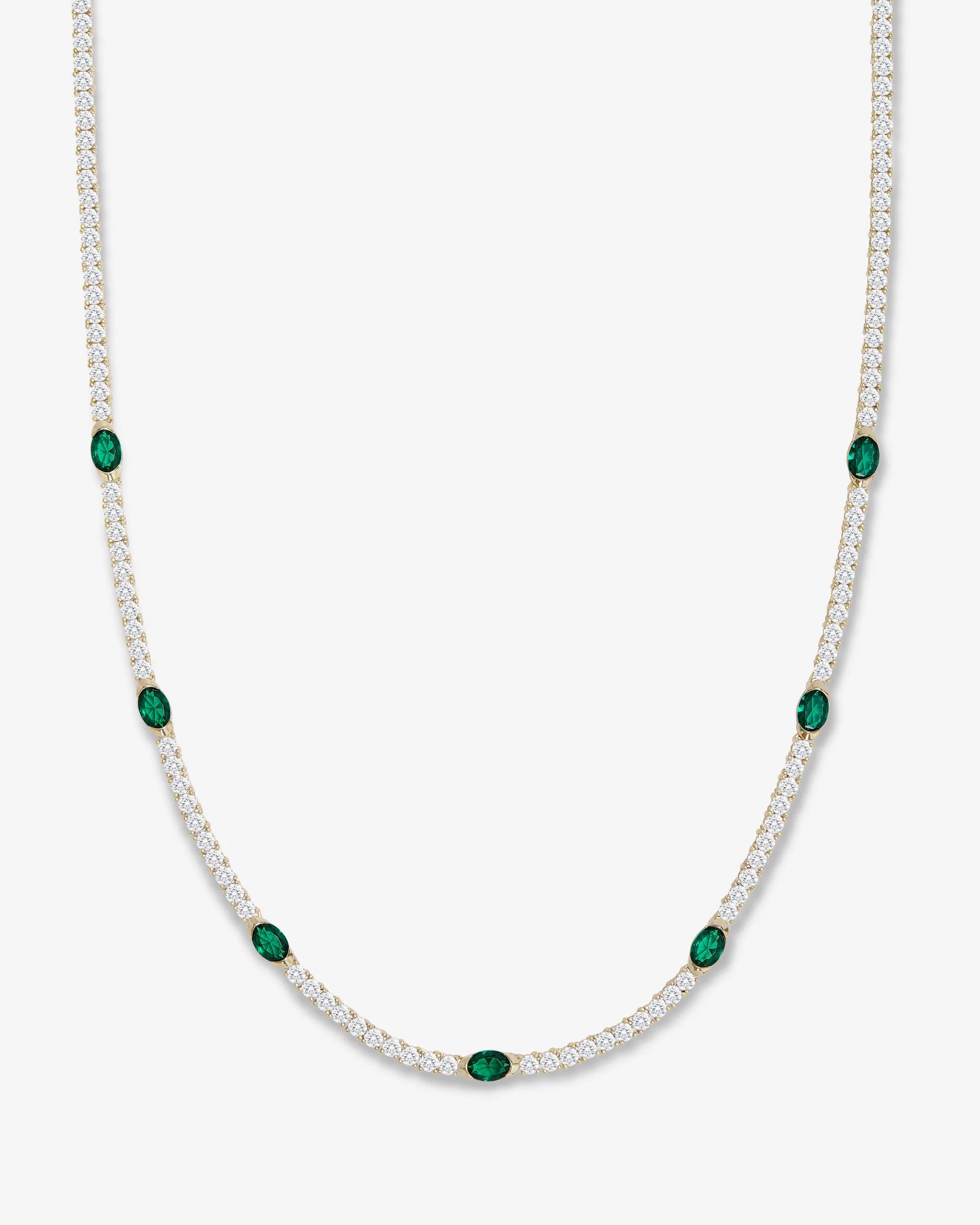 Gold necklace with green gemstones on a white background