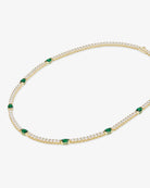Gold necklace with green gemstones on a white background