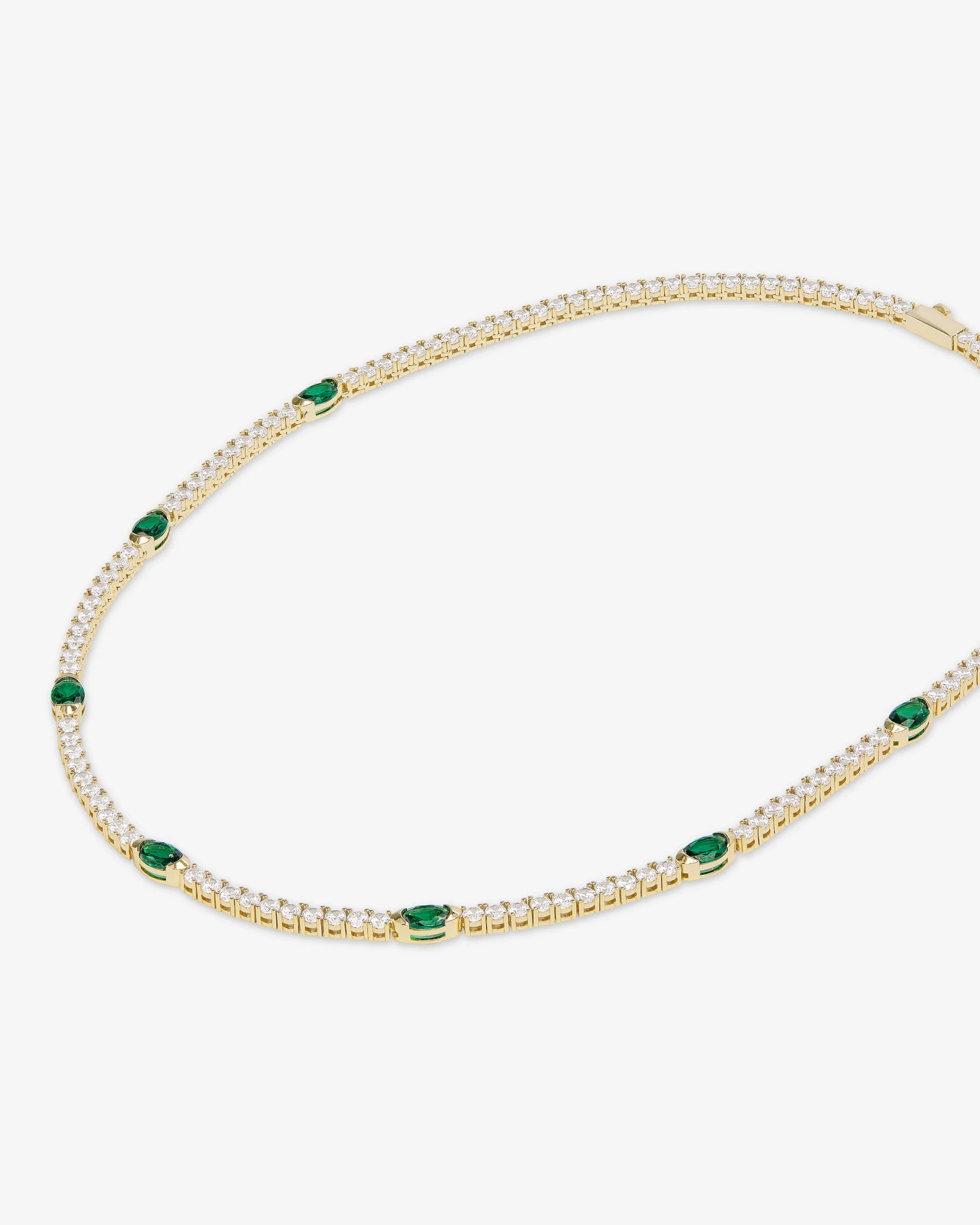 Gold necklace with green gemstones on a white background