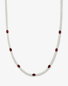 A delicate necklace featuring a double row of small white stones with spaced oval dark red gemstone accents, displayed on a clean light gray background.