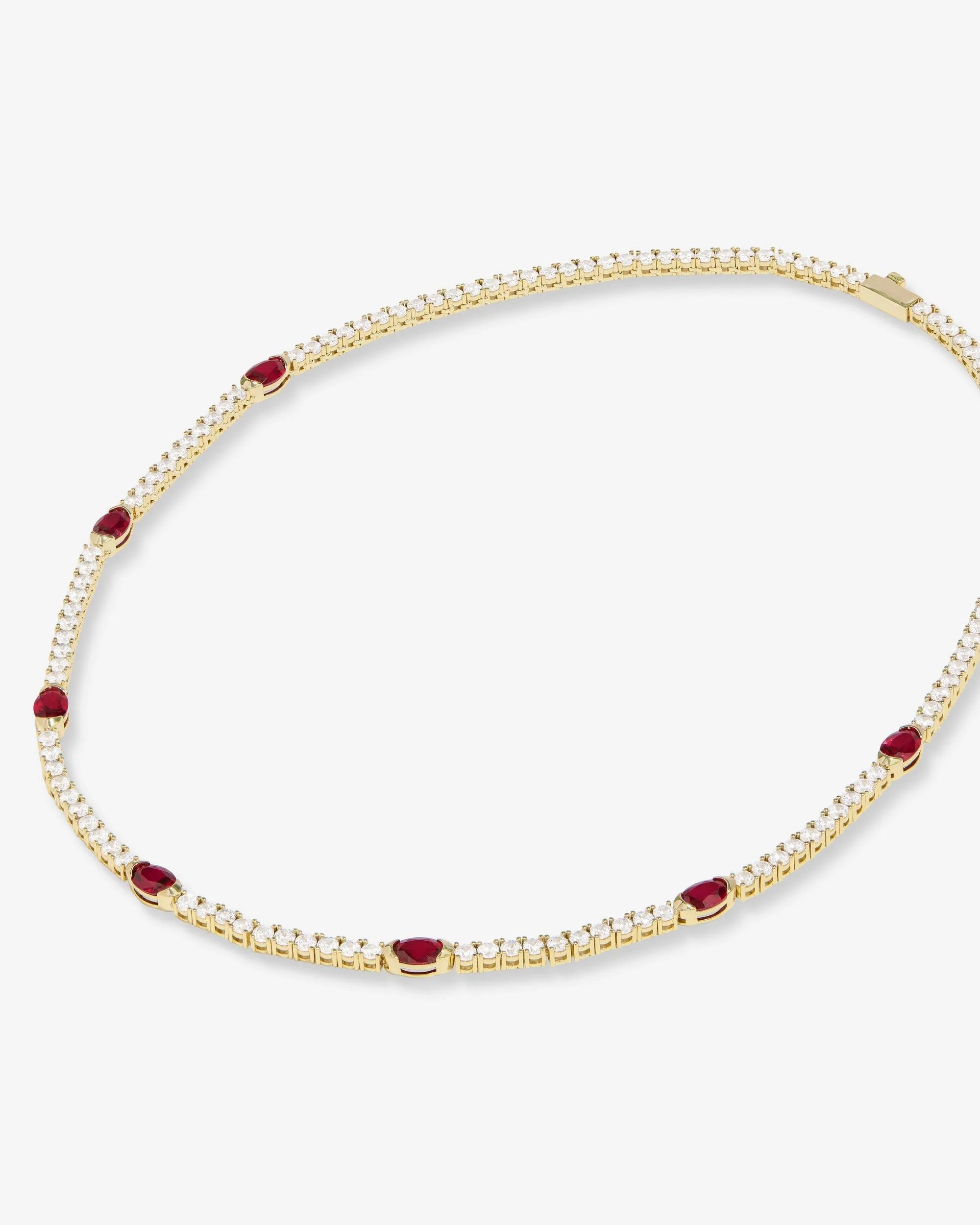 Gold necklace with red gemstones on a white background