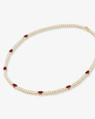 Gold necklace with red gemstones on a white background