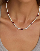 Necklace with red and clear beads on a person wearing a gray top