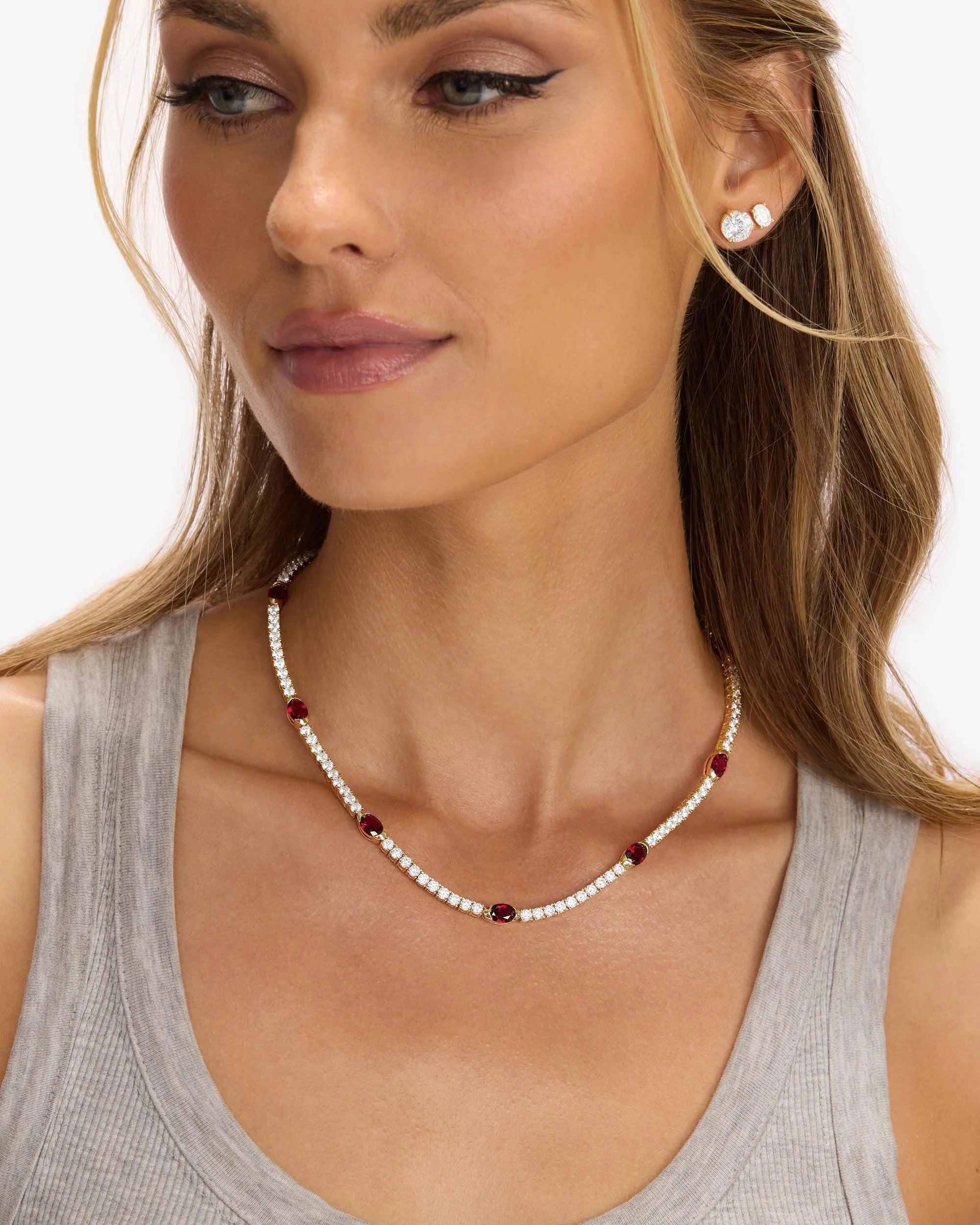 Woman wearing a pearl necklace with red beads on a plain background