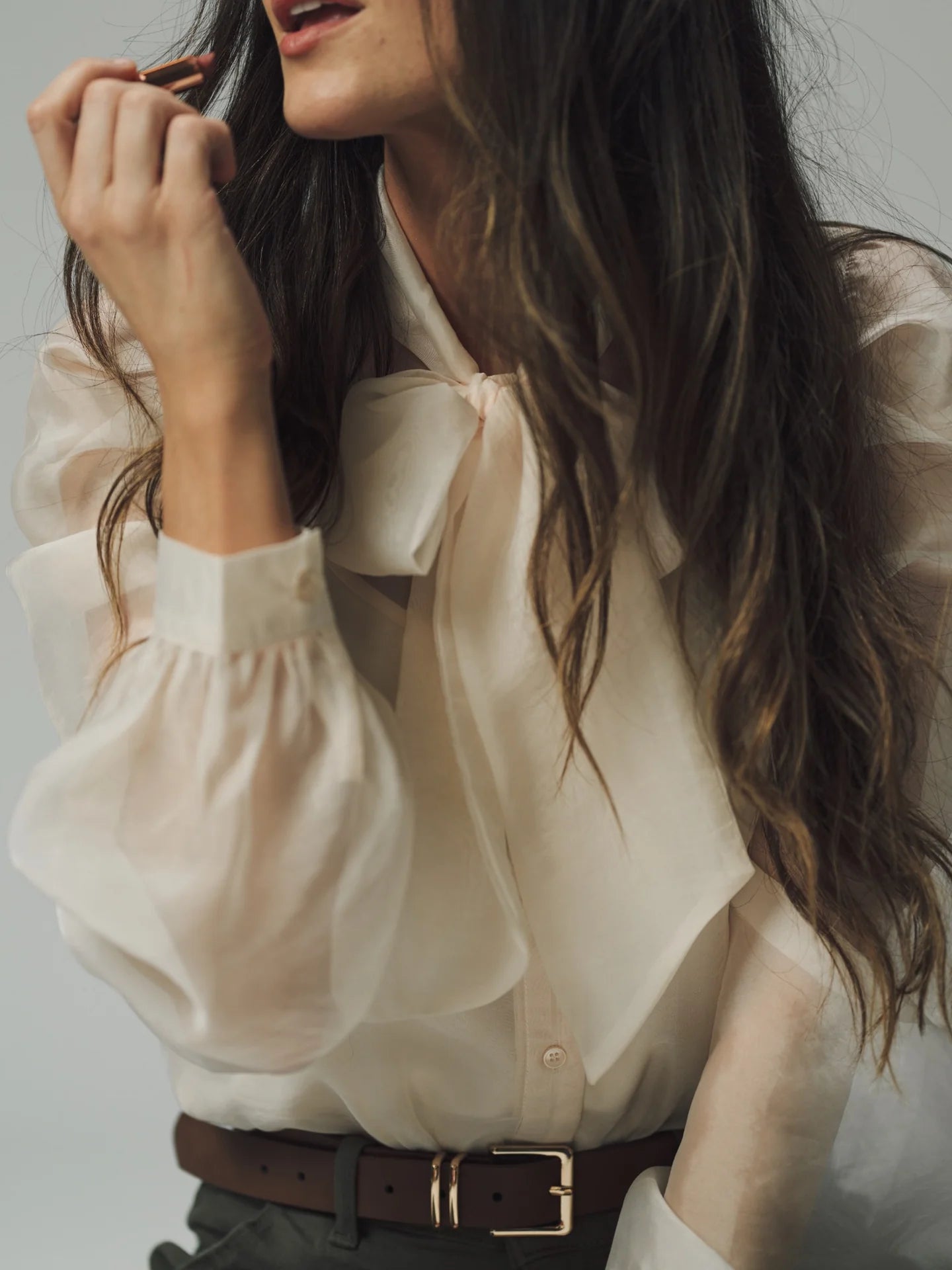 a woman wearing a white blouse with a big bow and long hair