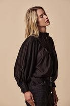 Woman wearing a black blouse against a yellow background