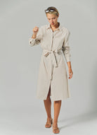 Woman wearing a beige striped shirt dress on a plain background