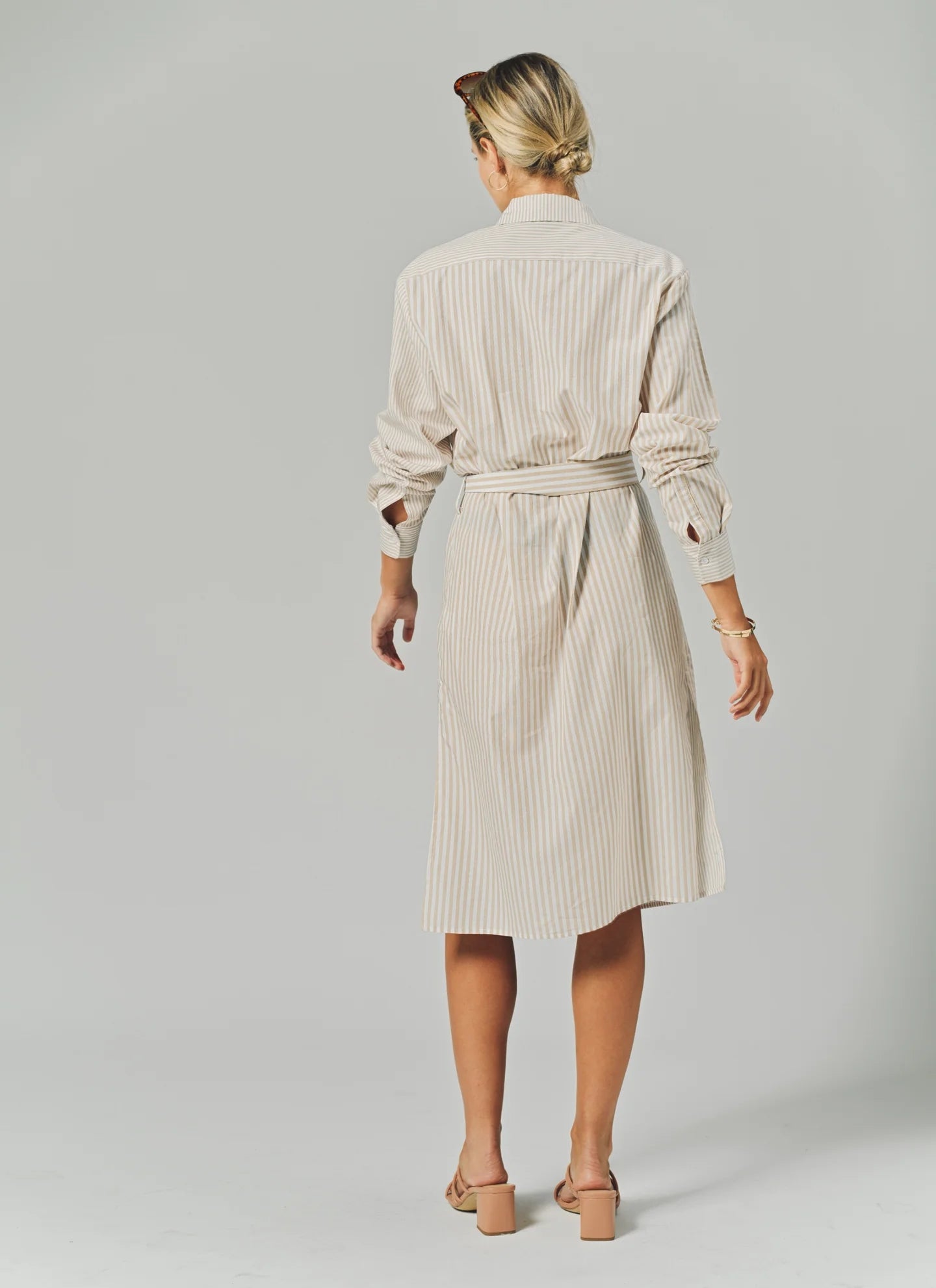 Woman wearing a beige striped dress on a plain background
