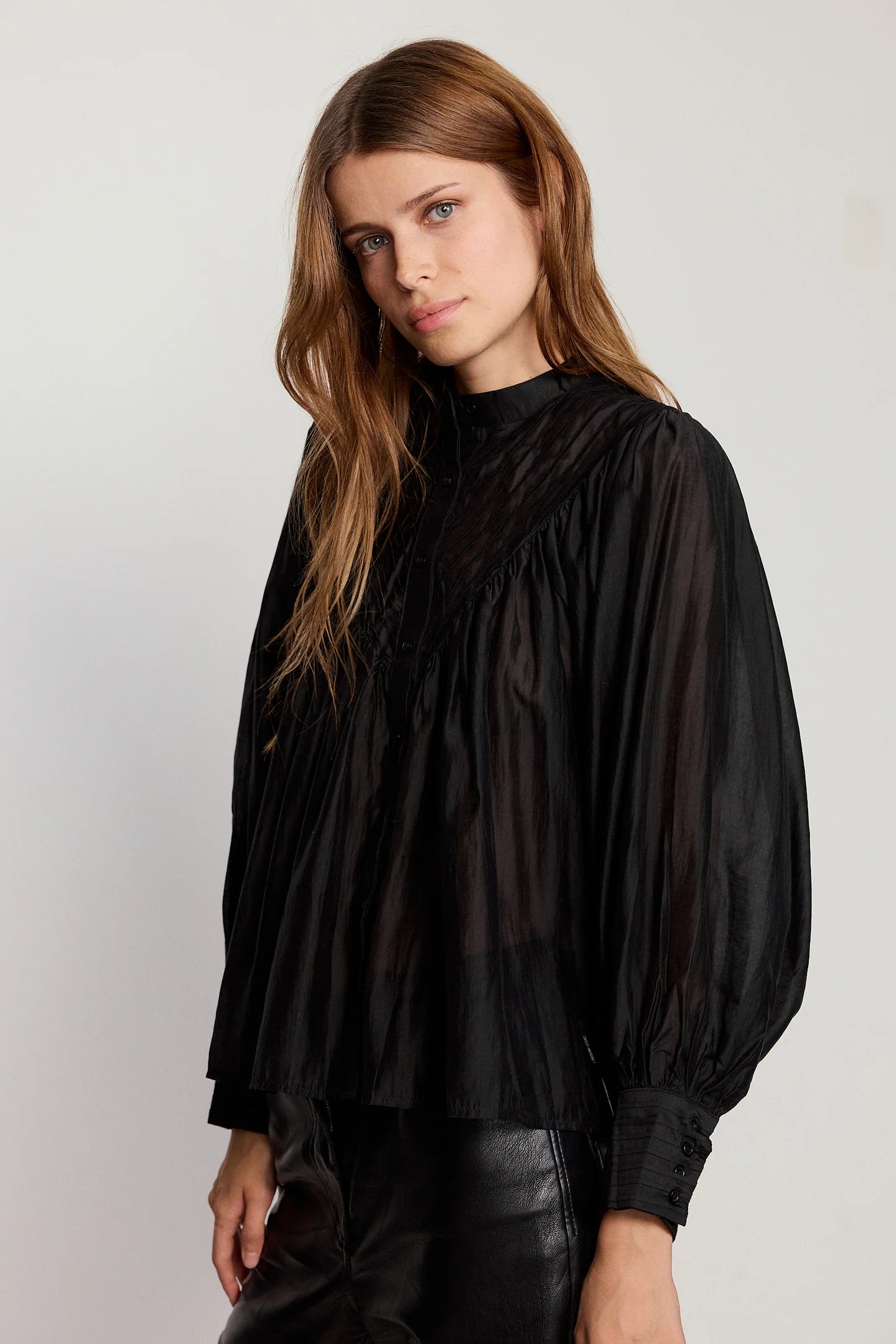 Woman wearing a black blouse with a plain background