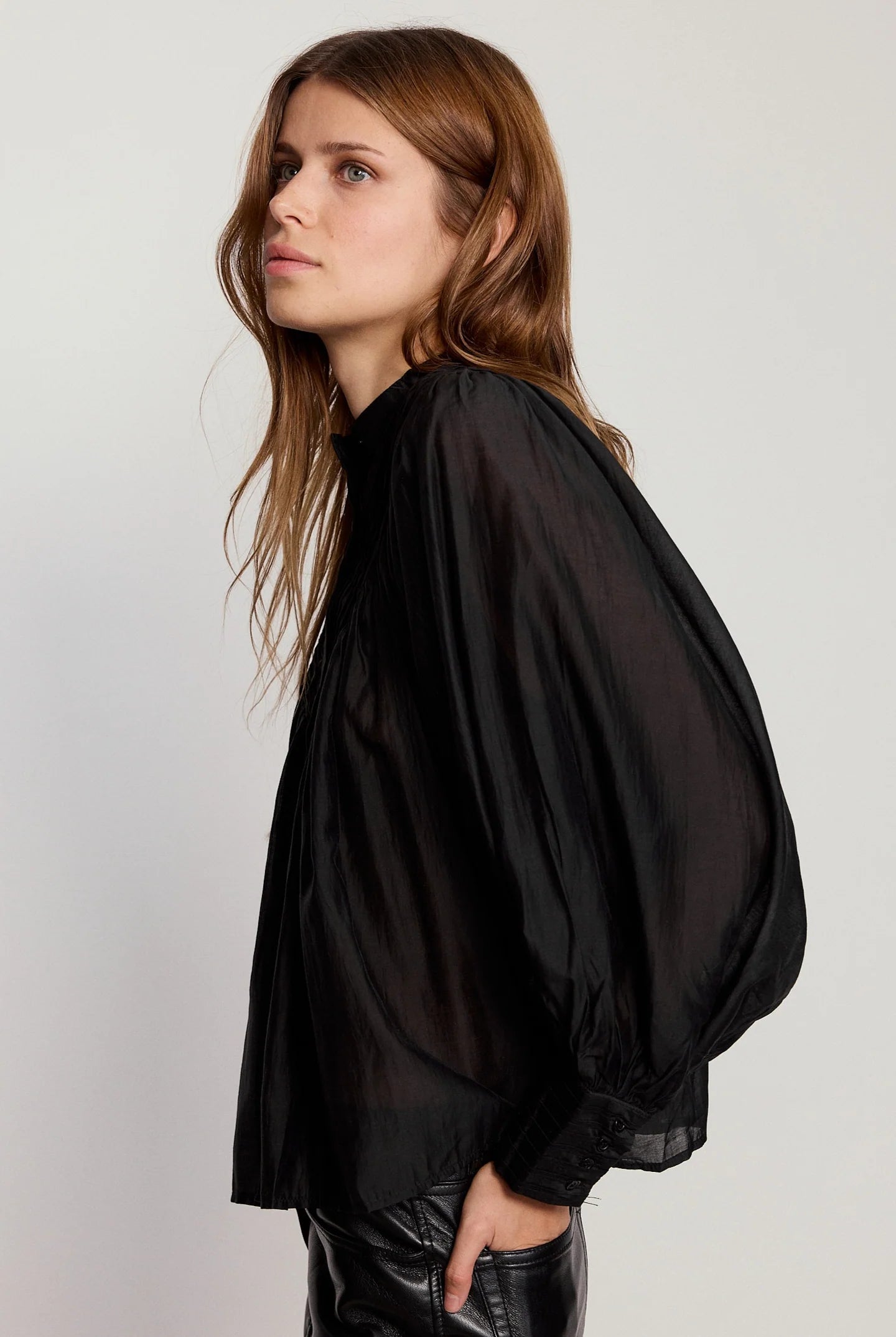 Woman wearing a black blouse with balloon sleeves against a white background