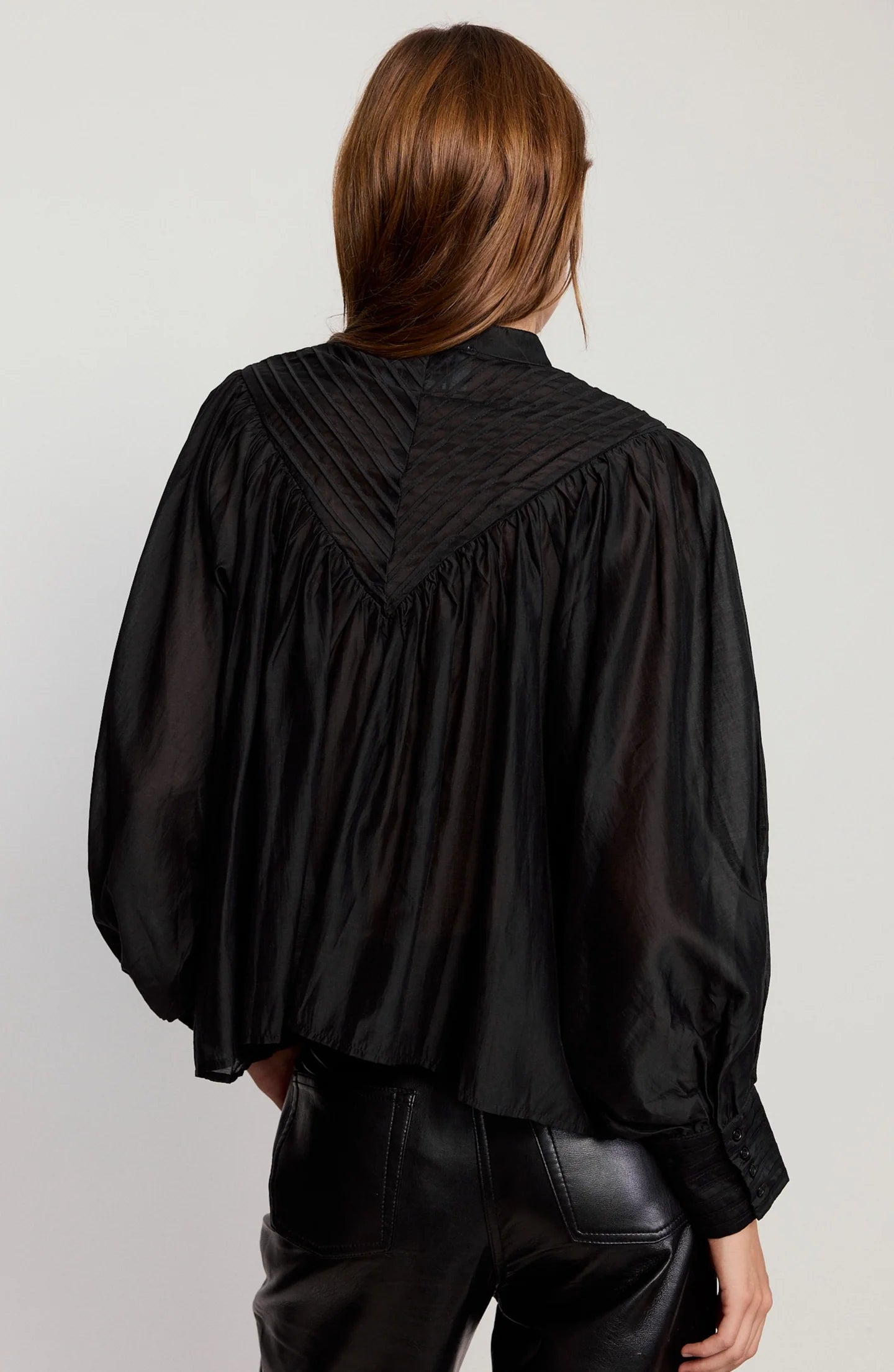 Person wearing a black blouse with puffed sleeves on a plain background