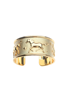 A gold-toned open cuff bracelet featuring raised zodiac symbols, including a horse and a ram, surrounded by small stars, shown on a plain white background.