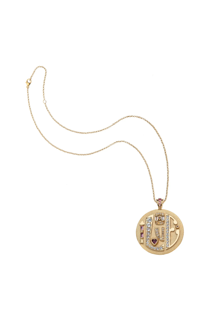 A gold pendant necklace featuring a detailed circular pendant with a central figure and small red and clear stones, displayed on a clean white background.