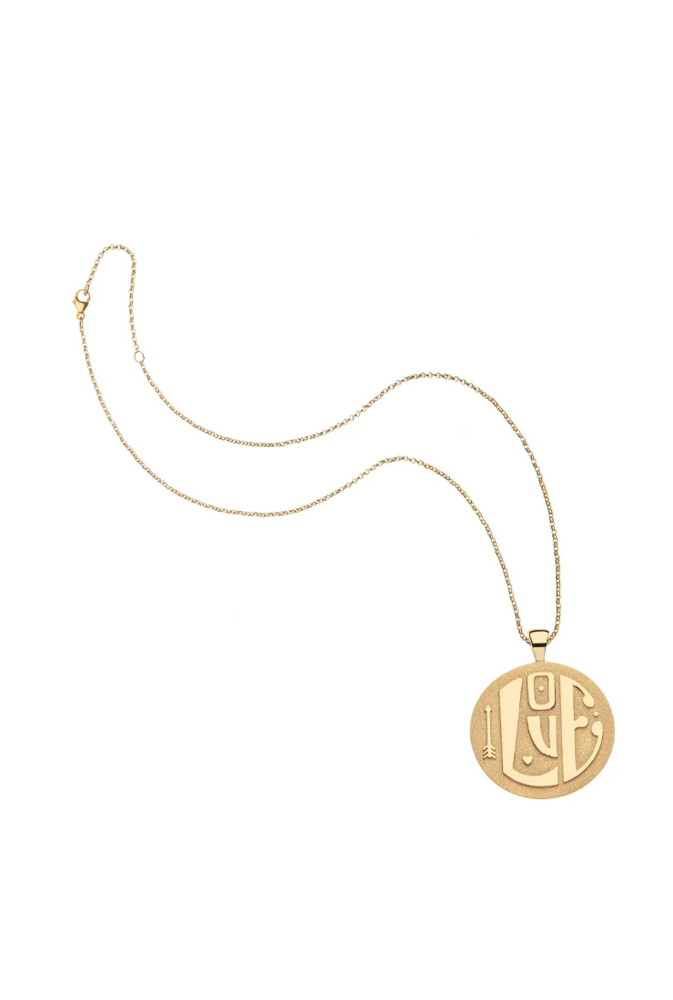 A gold pendant necklace featuring a circular disc pendant with stylized Arabic calligraphy, displayed on a clean white background.