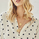 Woman wearing gold necklaces with a polka dot blouse