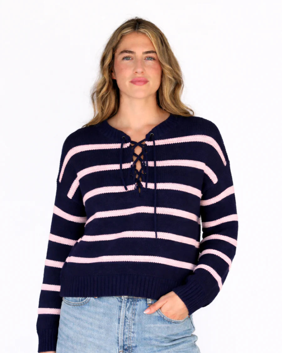 Woman wearing a navy and pink striped sweater on a white background