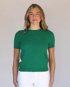 Woman wearing a green sweater against a plain background
