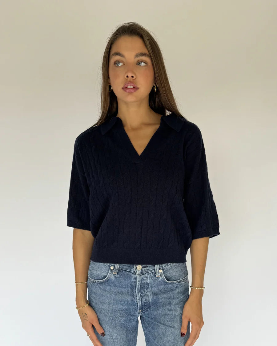 Woman wearing a black top and blue jeans against a plain background