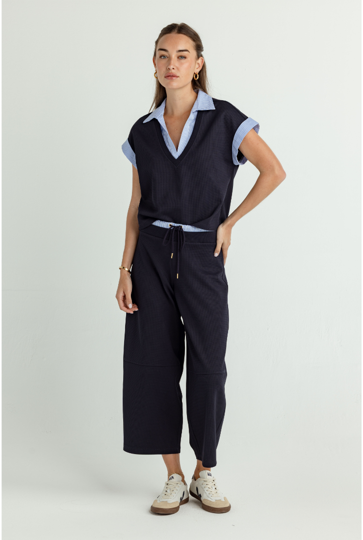 Woman wearing a navy outfit with a white background