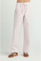 A person wearing light pink wide-leg drawstring pants and brown sneakers, shown from the waist down against a plain light gray studio background.