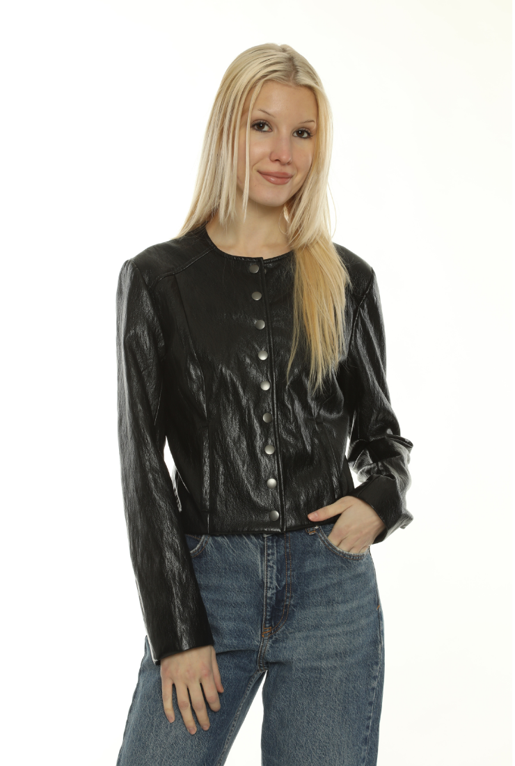 A blonde woman wearing a shiny black long-sleeve button-front jacket and blue jeans, standing against a plain white background.