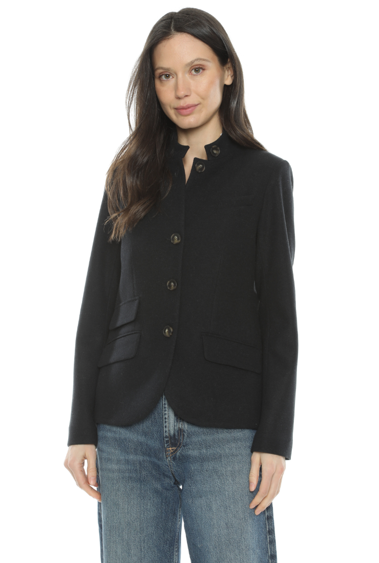 A woman modeling a black long-sleeve blazer with a band collar and three-quarter button closure, paired with blue jeans against a plain white background.