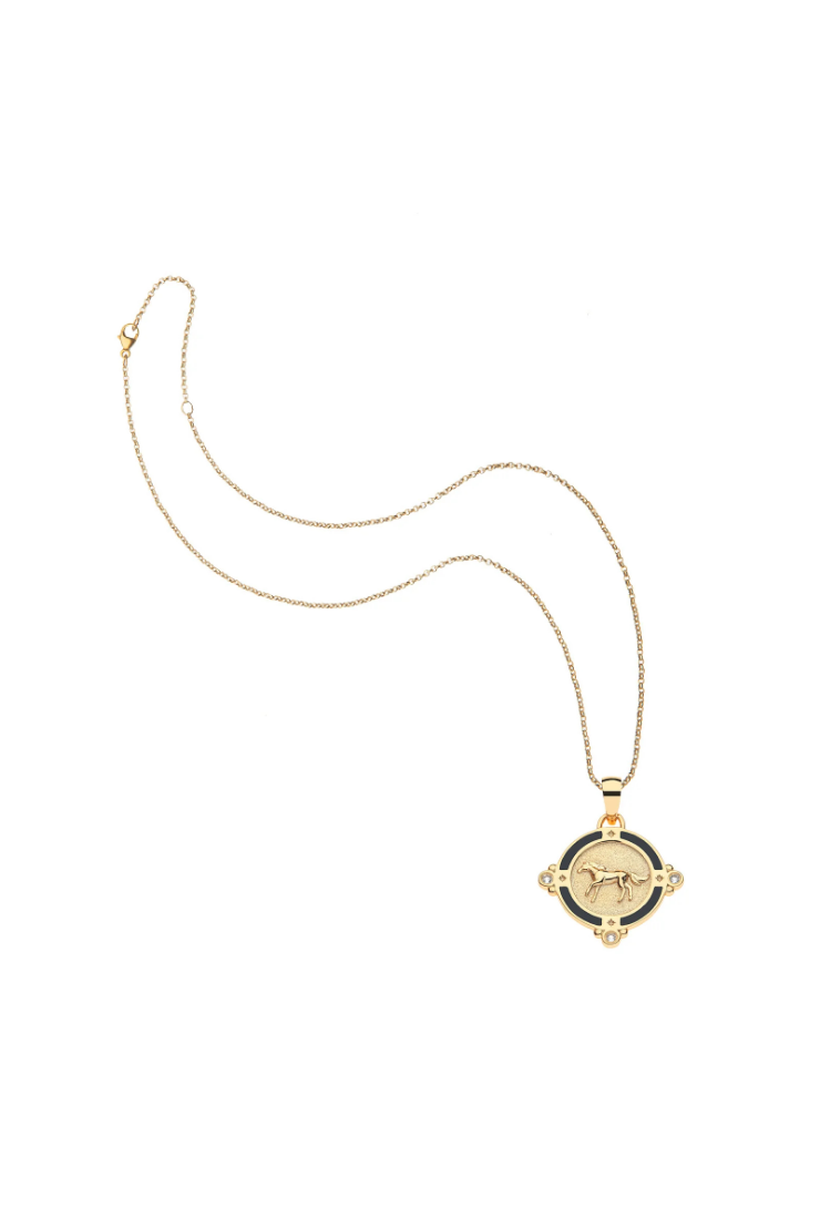 A gold pendant necklace featuring a circular black and gold compass design with a bull motif in the center, displayed on a clean white background.