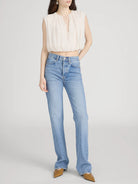 Woman wearing light blue jeans and a beige top on a white background