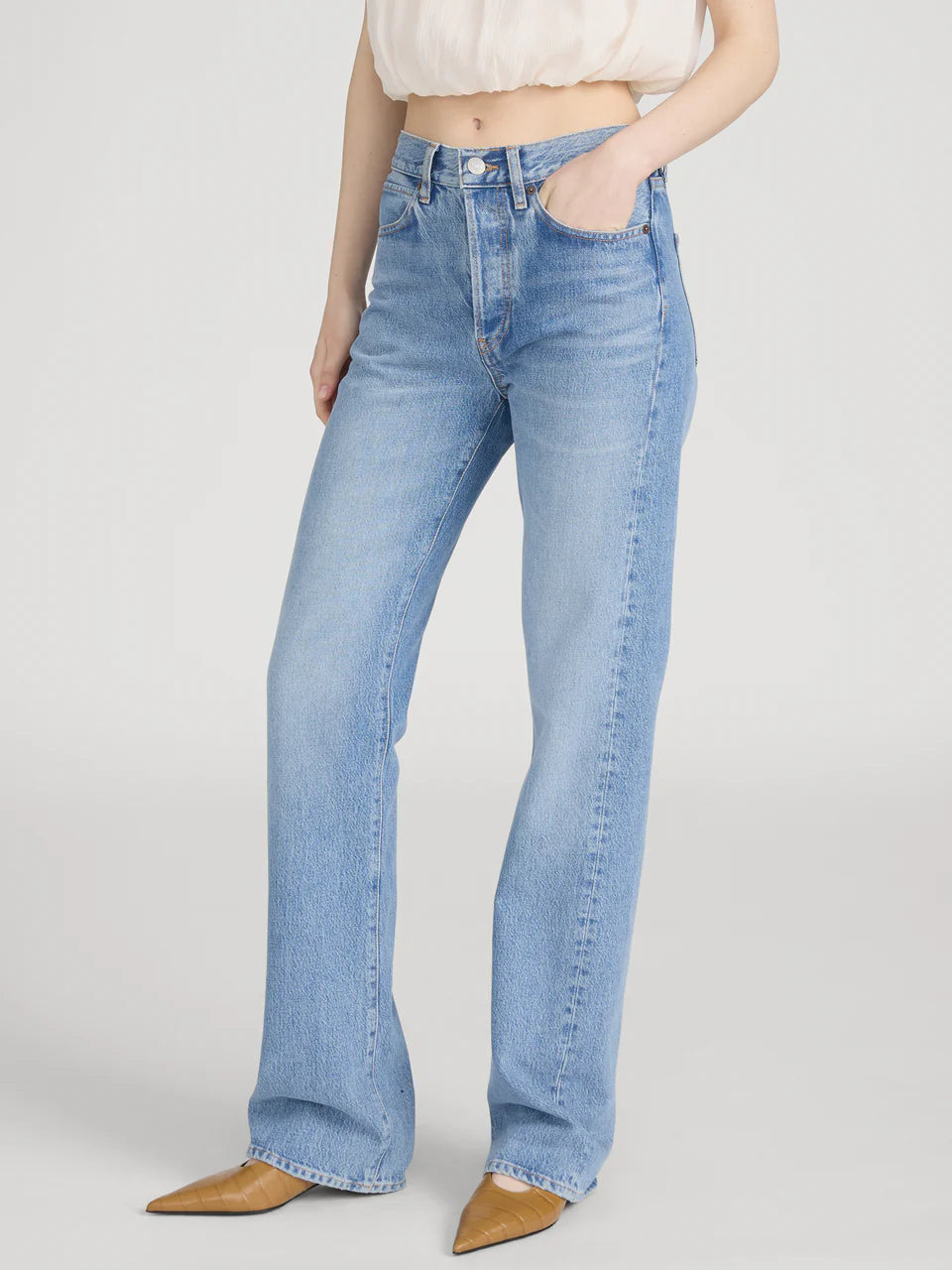 Person wearing light blue jeans on a plain background