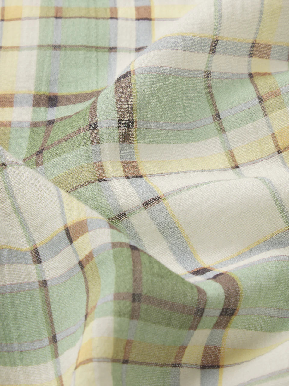 Close-up of plaid fabric with green, yellow, and brown colors.