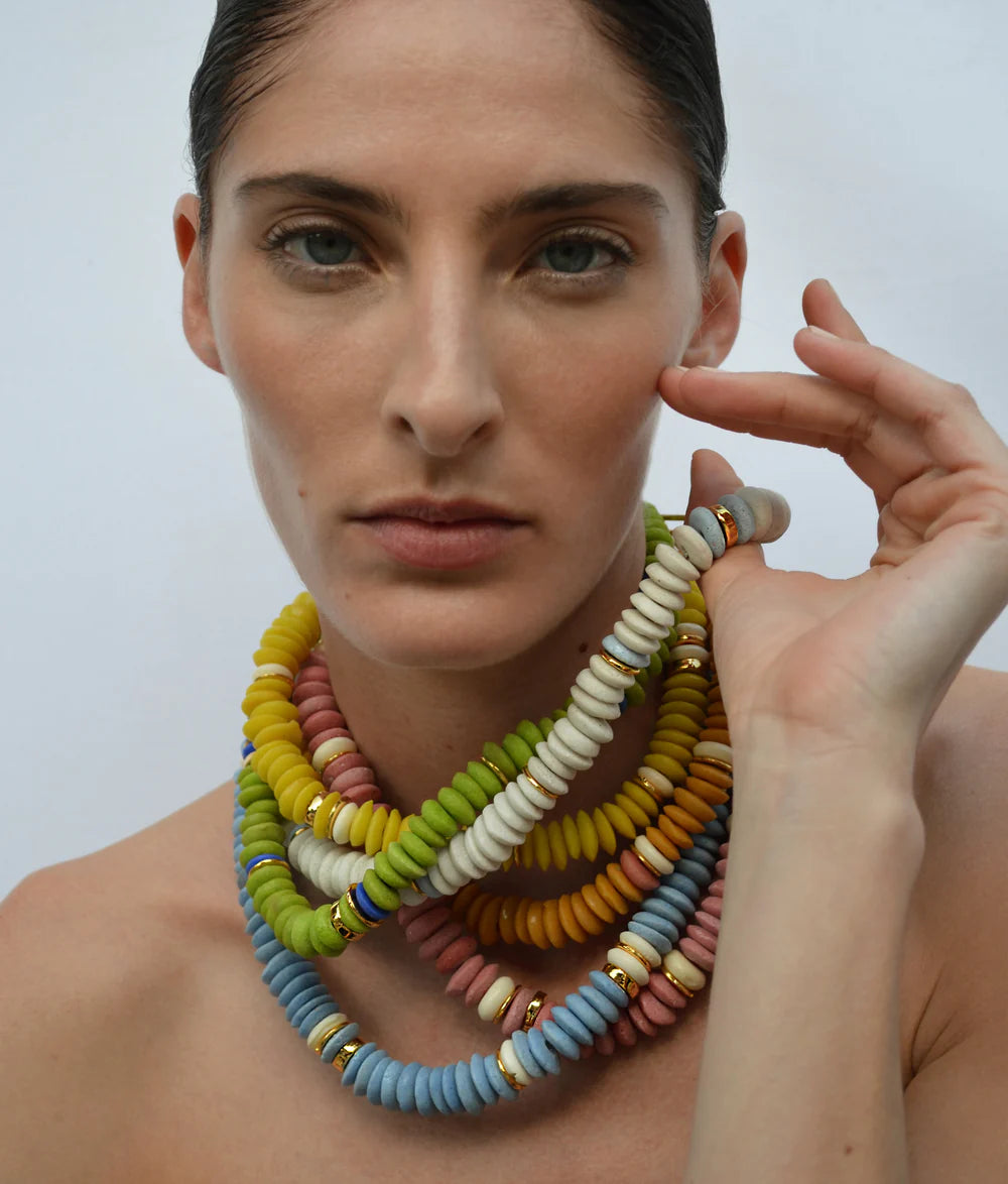 Woman wearing a colorful beaded necklace against a plain background