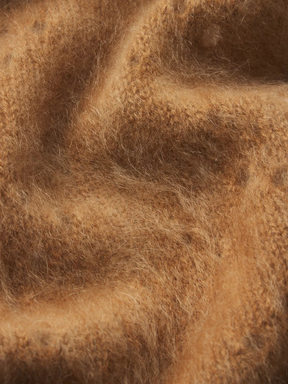 A close-up of soft, fuzzy brown fabric with a warm camel or tan tone and visible texture.