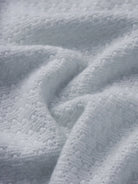 A close-up of a soft, textured white fabric with a plush, looped terry surface and gentle folds.
