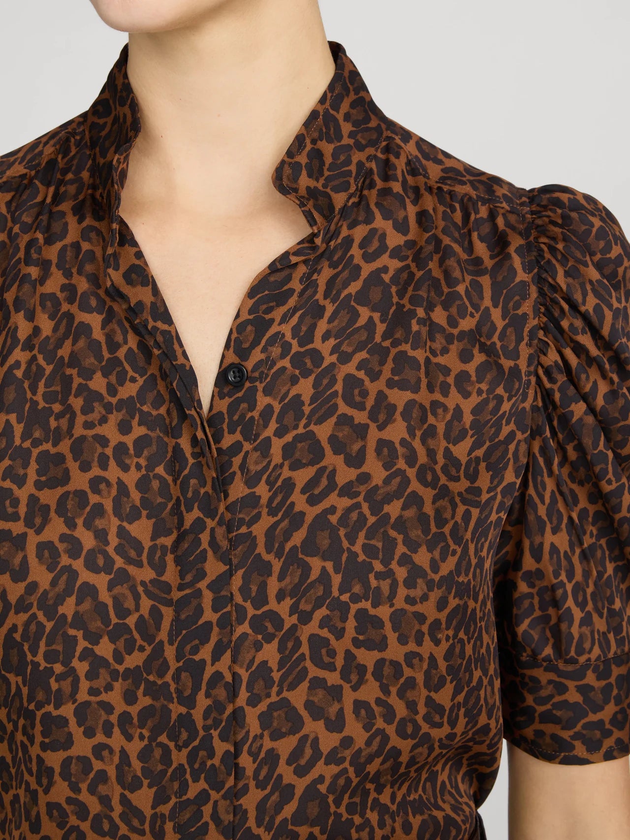 Close-up of a model wearing a brown and black leopard print blouse with puff sleeves and a split collar.