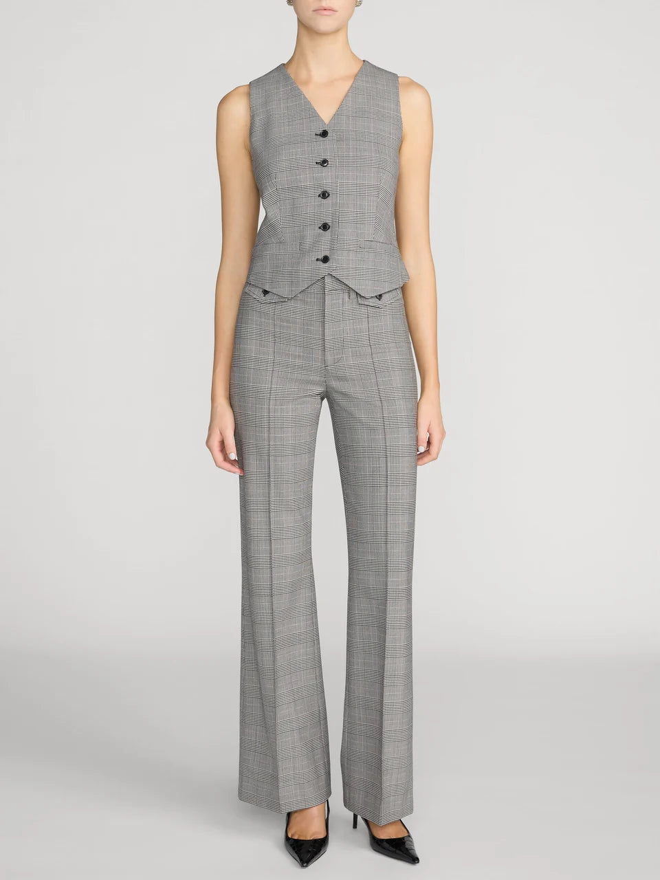 A model wearing a gray plaid sleeveless vest and matching wide-leg trousers, styled with black pointed-toe heels against a light gray studio background.