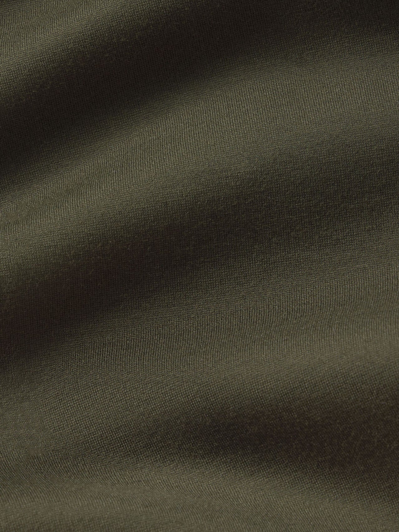 A close-up of dark olive green fabric with soft folds and a fine knit texture.